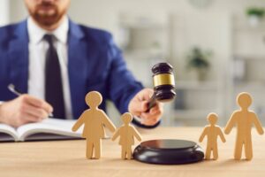 In family court, a lawyer delivers a verdict on divorce proceedings, wielding a gavel, beside wooden family figurines
